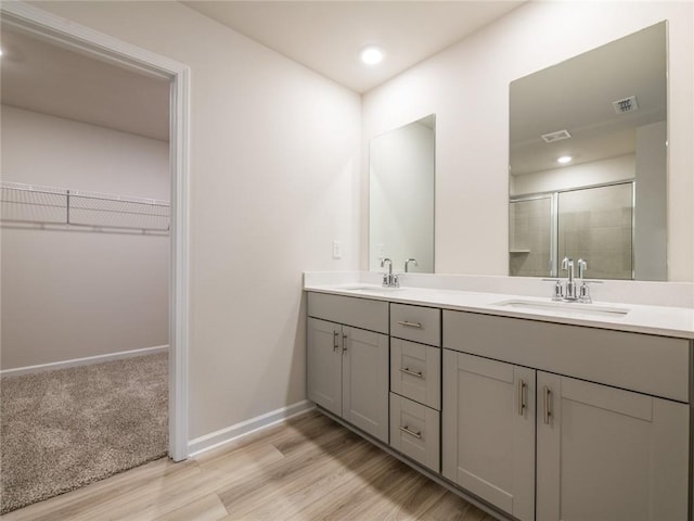 bathroom with hardwood / wood-style floors, vanity, and a shower with shower door