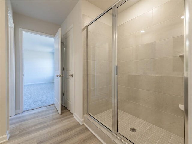 bathroom featuring wood-type flooring and a shower with shower door