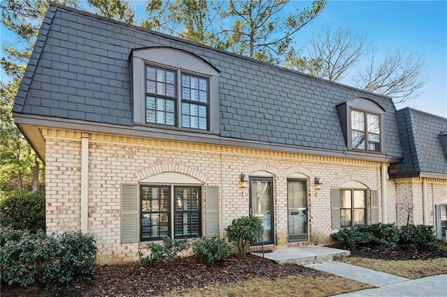 townhome / multi-family property with mansard roof and brick siding