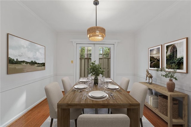 dining space featuring baseboards, ornamental molding, wood finished floors, and french doors