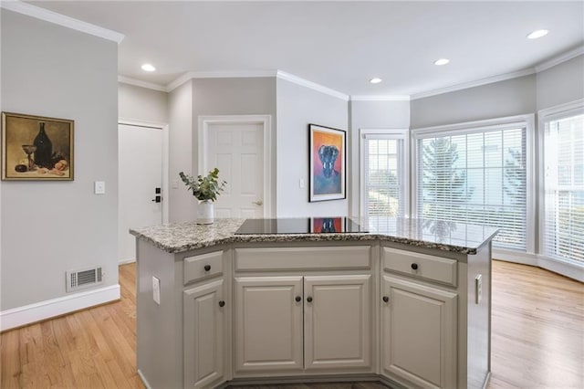 kitchen with light stone countertops, a center island, ornamental molding, and light wood-type flooring