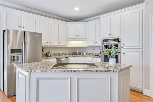 kitchen featuring light wood-type flooring, appliances with stainless steel finishes, white cabinetry, and a kitchen island