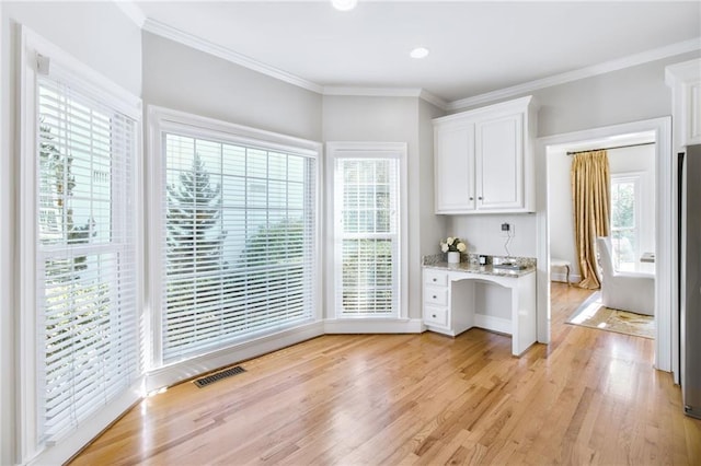 bar with white cabinetry, plenty of natural light, built in desk, light hardwood / wood-style flooring, and light stone counters