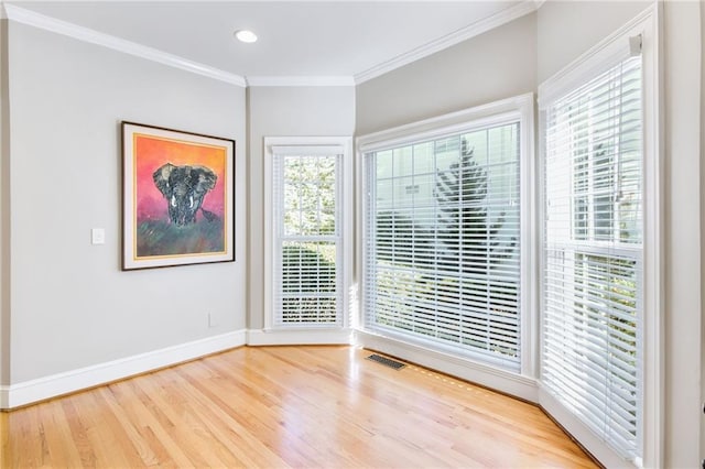 unfurnished room featuring plenty of natural light, hardwood / wood-style floors, and ornamental molding