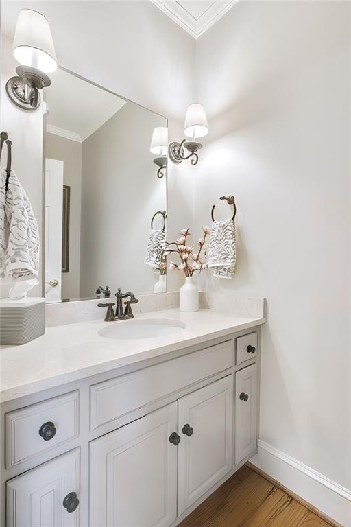 bathroom featuring hardwood / wood-style floors, vanity, and ornamental molding