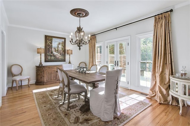 dining room with light hardwood / wood-style floors, crown molding, french doors, and an inviting chandelier