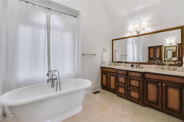 bathroom with tile patterned flooring, vanity, a tub, and vaulted ceiling