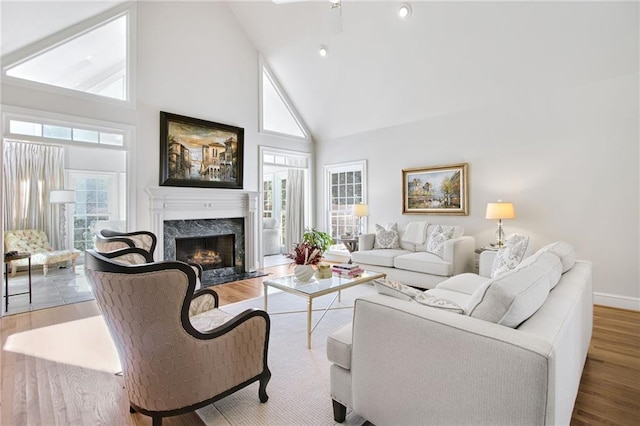 living room with high vaulted ceiling, hardwood / wood-style floors, and a premium fireplace