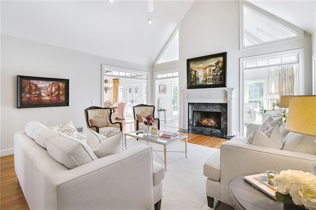 living room with high vaulted ceiling, a fireplace, and hardwood / wood-style floors