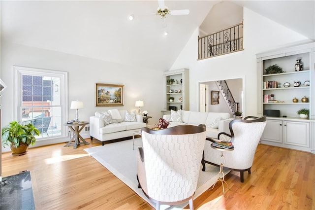 living room with ceiling fan, light wood-type flooring, and high vaulted ceiling