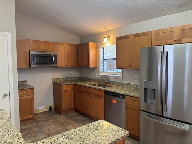 kitchen featuring light stone countertops, a textured ceiling, lofted ceiling, stainless steel appliances, and sink