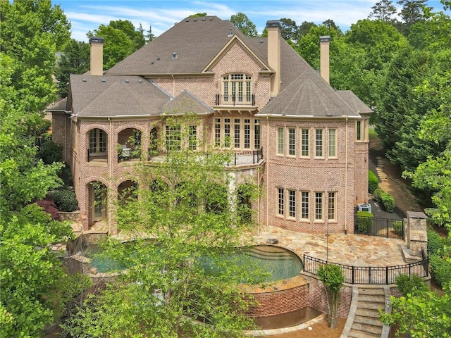 back of house with a patio area, a chimney, and brick siding