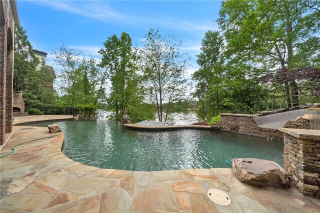 outdoor pool with an outdoor stone fireplace, a patio area, and fence