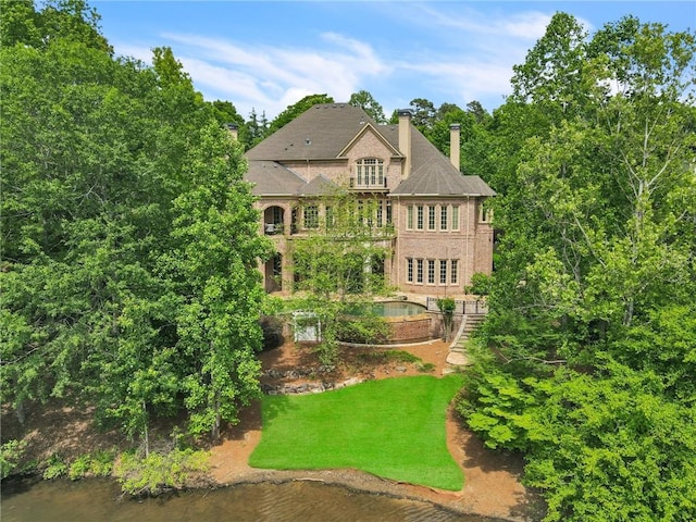 exterior space featuring a water view, a lawn, and a chimney