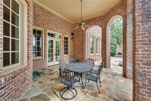 view of patio / terrace with outdoor dining space, french doors, a fireplace, and ceiling fan