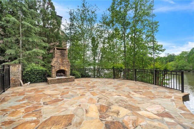 view of patio / terrace featuring a water view and an outdoor stone fireplace