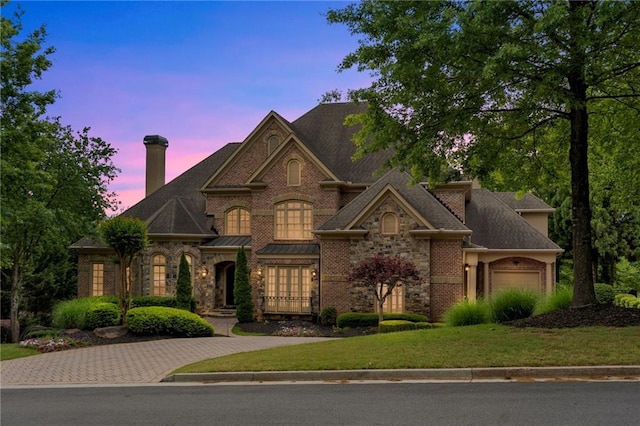 view of front facade with a garage, driveway, brick siding, and a front yard