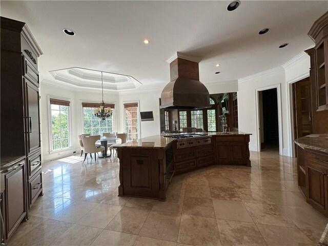 kitchen featuring tasteful backsplash, brown cabinetry, stainless steel gas stovetop, island exhaust hood, and a fireplace