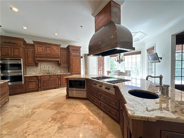 kitchen featuring crown molding, a tray ceiling, island exhaust hood, and stainless steel gas stovetop