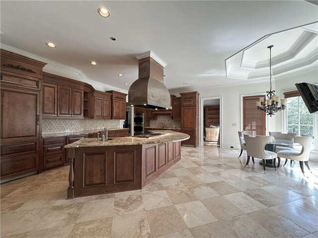 kitchen featuring stainless steel appliances, decorative backsplash, a healthy amount of sunlight, a sink, and island range hood