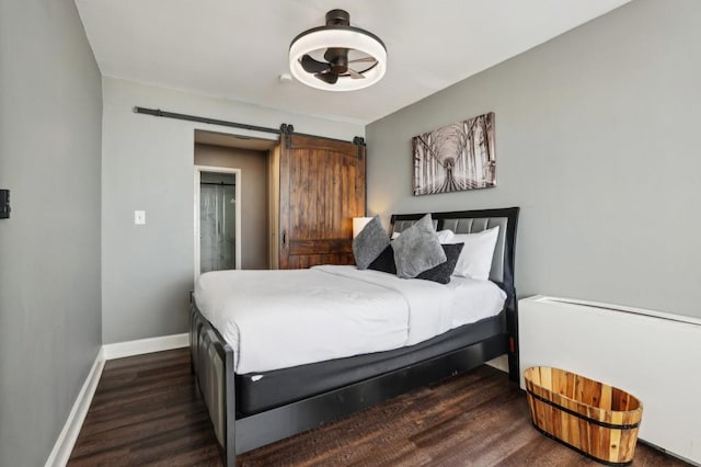 bedroom featuring a barn door, wood finished floors, and baseboards