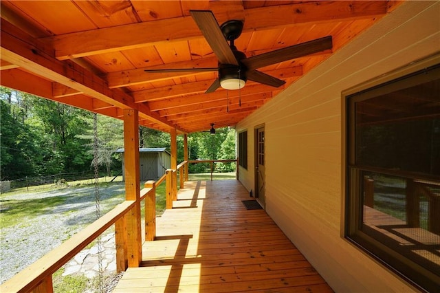 wooden terrace featuring ceiling fan and a storage shed