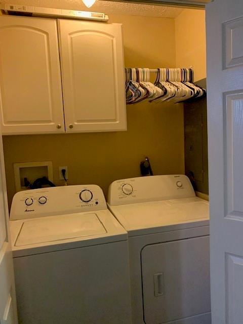 clothes washing area featuring washing machine and dryer and cabinets