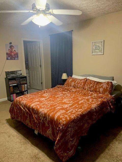 carpeted bedroom featuring ceiling fan and a textured ceiling