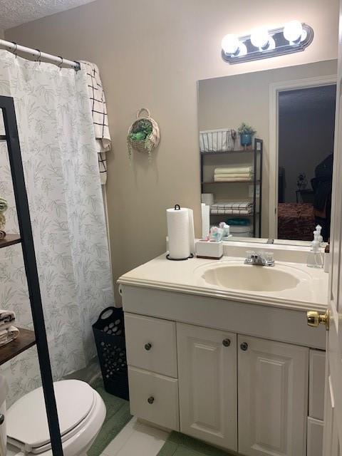 bathroom with vanity, a textured ceiling, a shower with curtain, and toilet