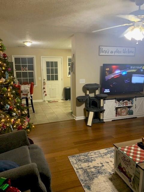 living room featuring ceiling fan, wood-type flooring, and a textured ceiling