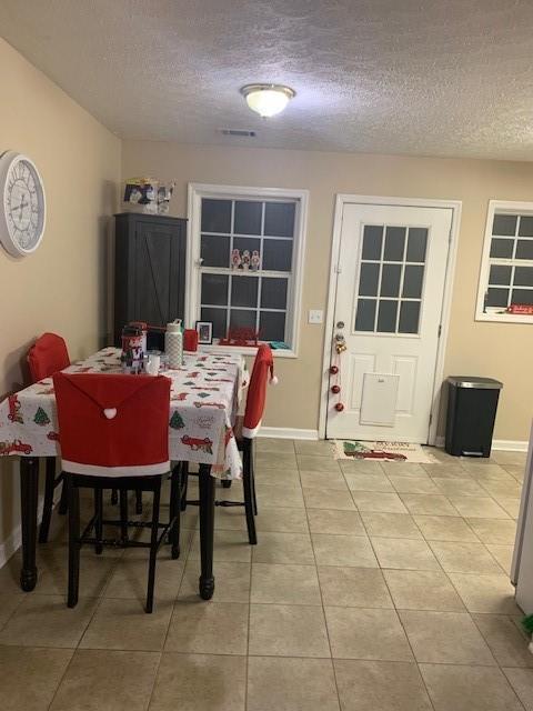 dining area with a textured ceiling and light tile patterned flooring