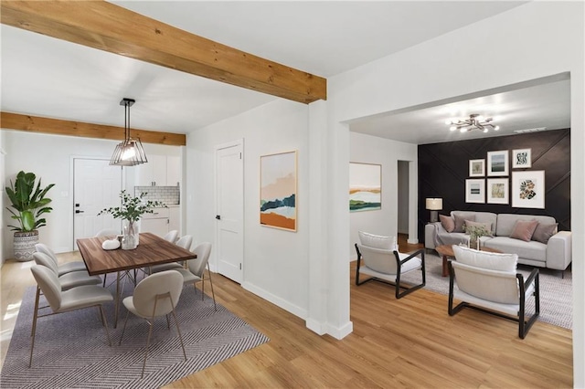 dining room with beam ceiling, light hardwood / wood-style floors, and a notable chandelier