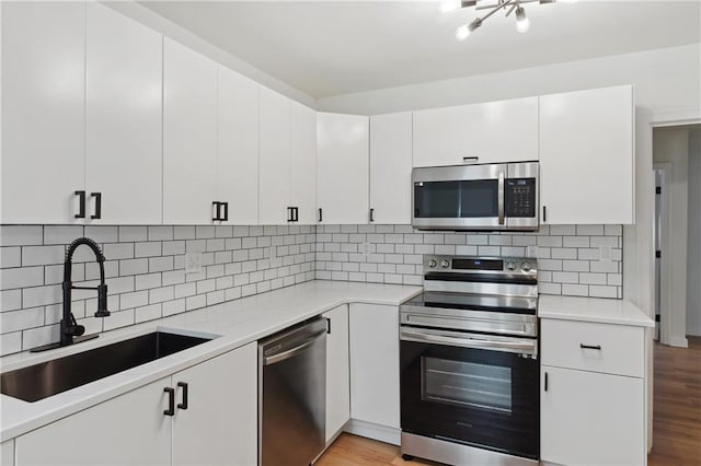 kitchen with white cabinetry, sink, stainless steel appliances, and light wood-type flooring