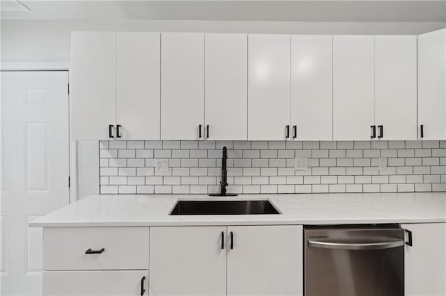 kitchen featuring white cabinetry, stainless steel dishwasher, light stone countertops, and sink