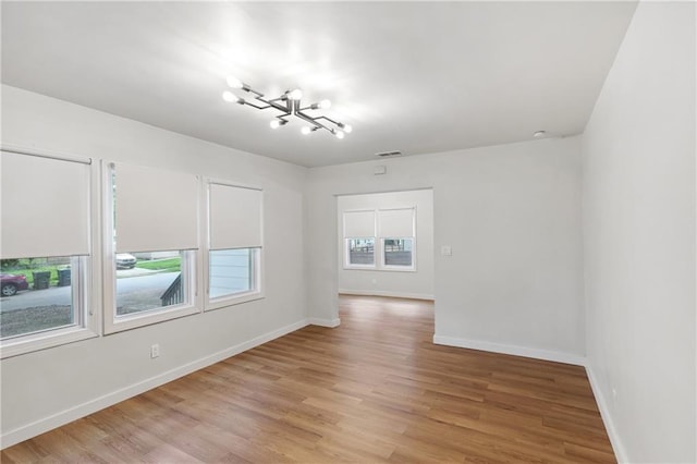 empty room with an inviting chandelier and light wood-type flooring