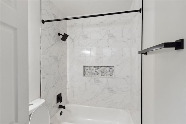 bathroom featuring tiled shower / bath combo and toilet