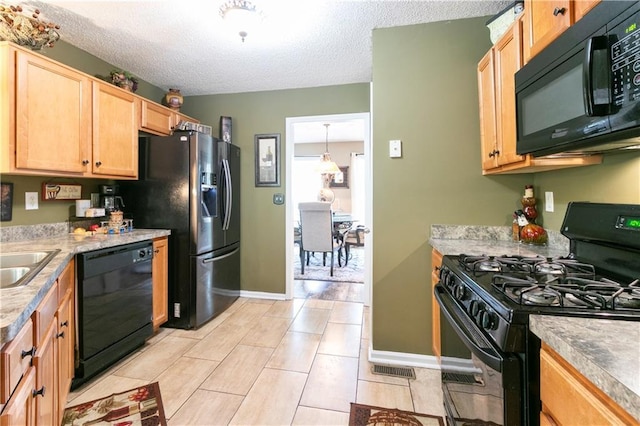kitchen with a textured ceiling, light brown cabinetry, black appliances, and baseboards