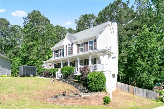 colonial-style house with a front lawn, covered porch, and fence