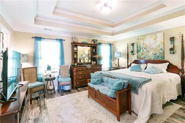 bedroom featuring ornamental molding, light wood finished floors, a tray ceiling, and visible vents