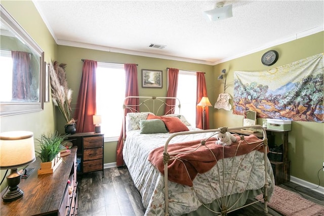 bedroom with dark wood finished floors, a textured ceiling, visible vents, and ornamental molding