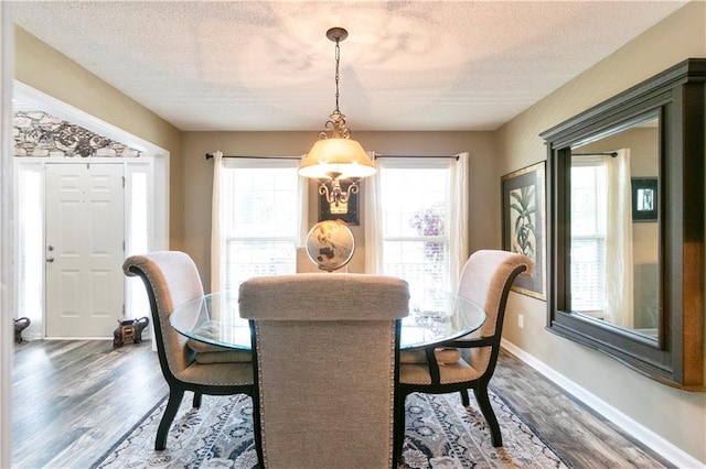 dining area featuring an inviting chandelier, a textured ceiling, baseboards, and dark wood-style floors