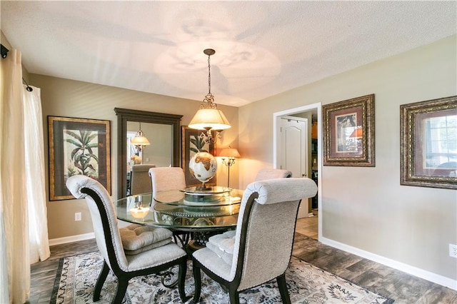 dining room featuring a textured ceiling, dark wood-type flooring, and baseboards
