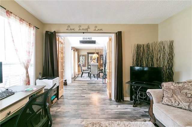living room with a textured ceiling, wood finished floors, and a healthy amount of sunlight