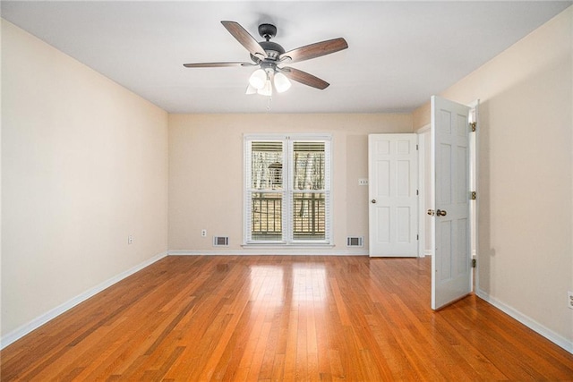 empty room with light wood-style floors, visible vents, and baseboards