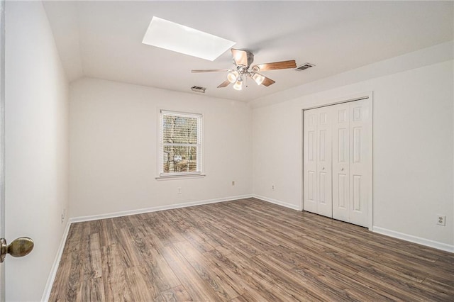 unfurnished bedroom featuring a skylight, baseboards, dark wood-style floors, and visible vents