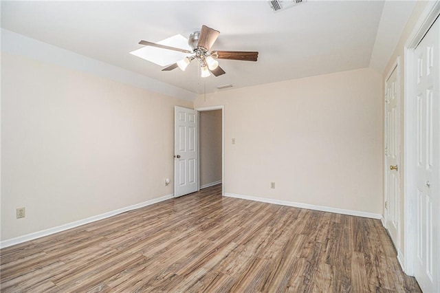 unfurnished bedroom featuring a skylight, visible vents, ceiling fan, wood finished floors, and baseboards