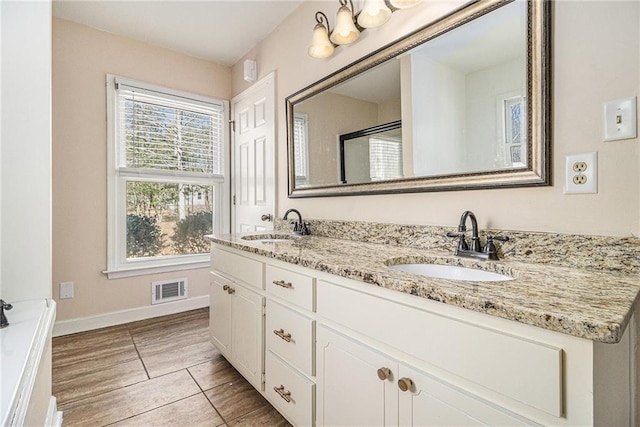 bathroom featuring double vanity, a sink, visible vents, and baseboards