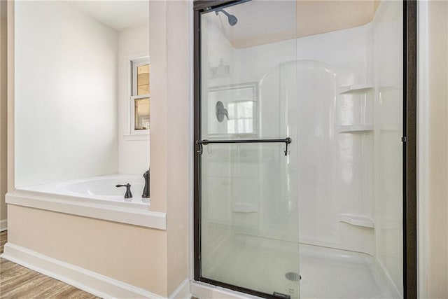 bathroom with a shower stall, a bath, and wood finished floors