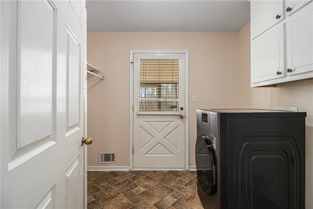 laundry room with visible vents, baseboards, cabinet space, stone finish floor, and washer / dryer