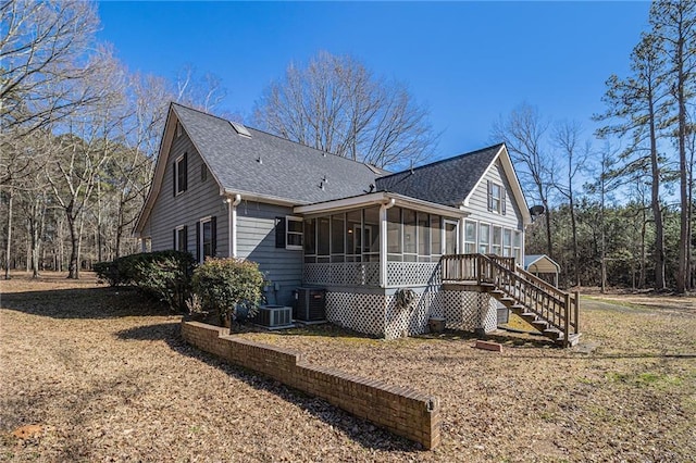 exterior space with a shingled roof, a sunroom, and stairway